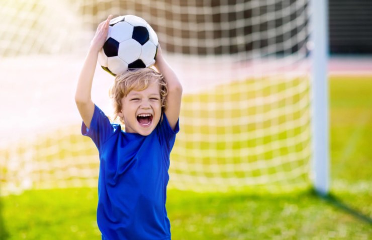 bambino che sorride con in mano un pallone da calcio