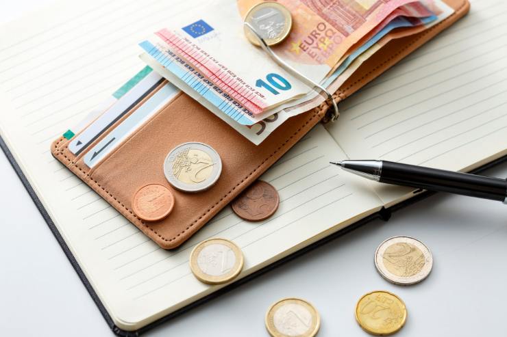 portafogli con monete e banconote euri sopra agenda con penna