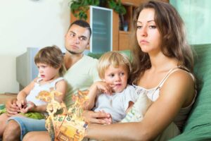 coppia triste con due figli in braccio e soldi che bruciano