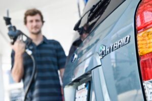 auto ibrida in primo piano e sullo sfondo uomo che sta per caricarla